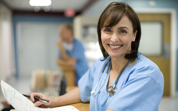 smiling nurse standing at nurses station smiling nurse standing at nurses station