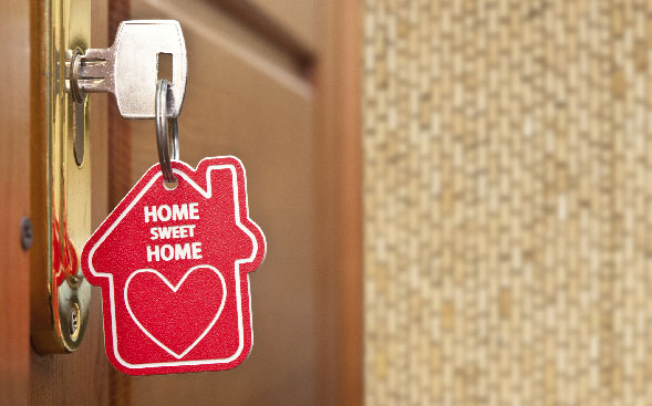 Home sweet home keychain on key hanging out of door Home sweet home keychain on key hanging out of door