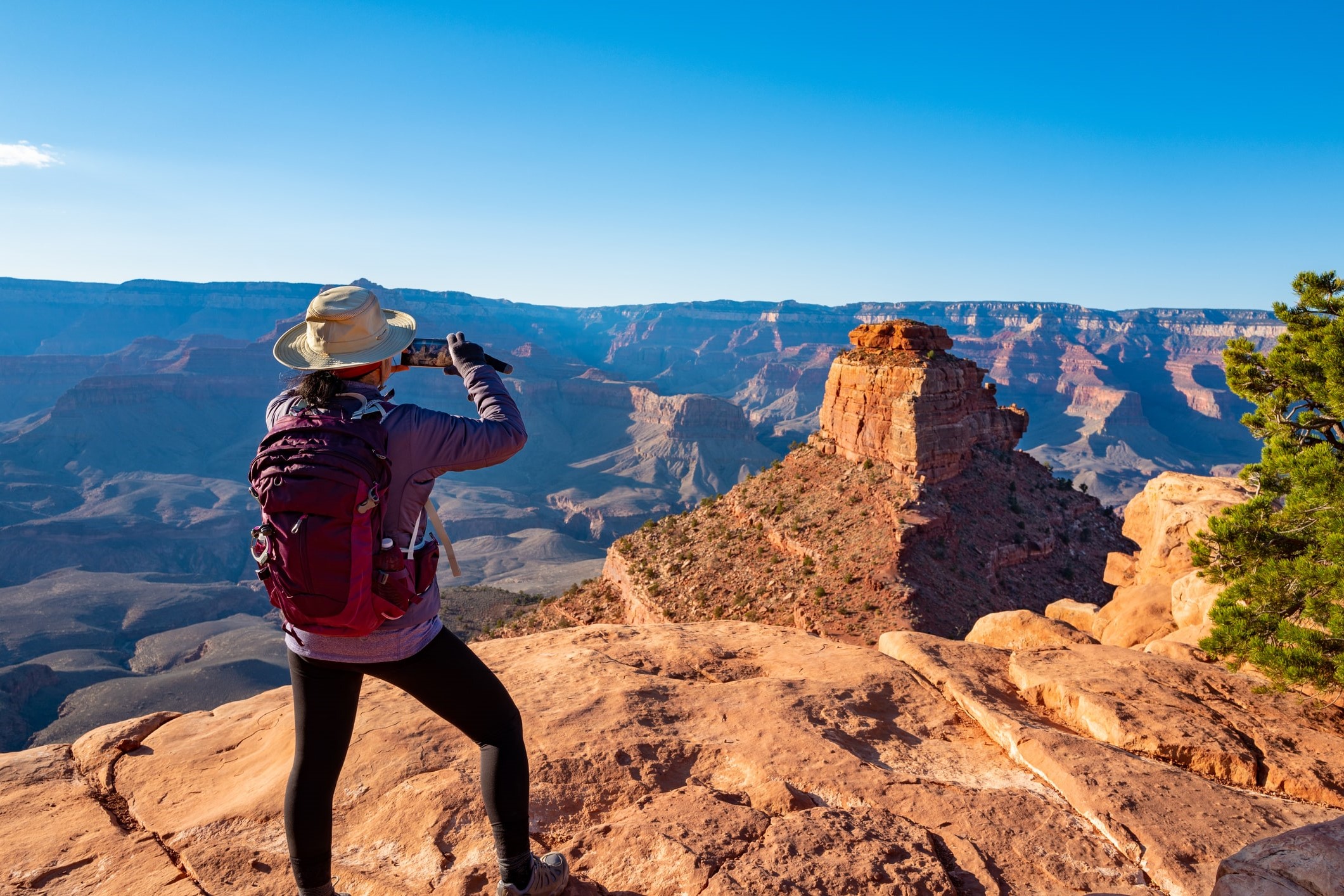 Female hiker wearing a backpack and looking across canyon